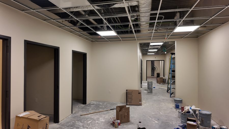 A commercial interior with painted walls, dark doors and an open ceiling grid