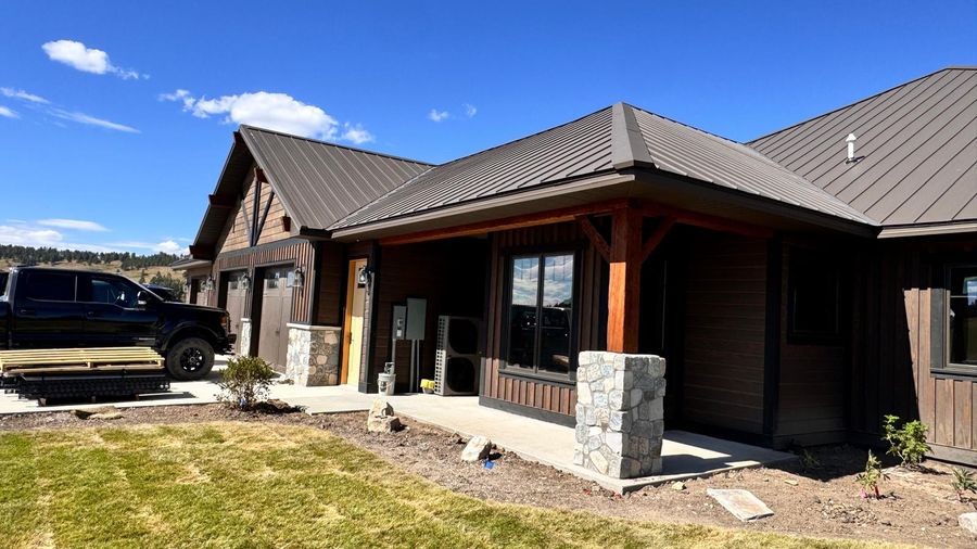 Front of a custom home with stone column bases and a metal roof