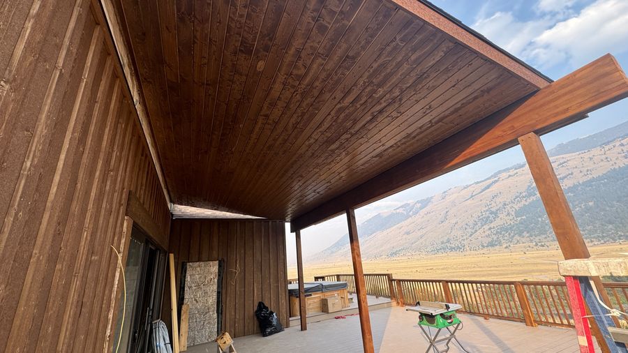 A covered porch with a stained tongue-and-groove ceiling