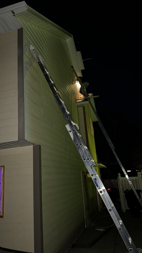 Ladders against a house exterior lit after dark