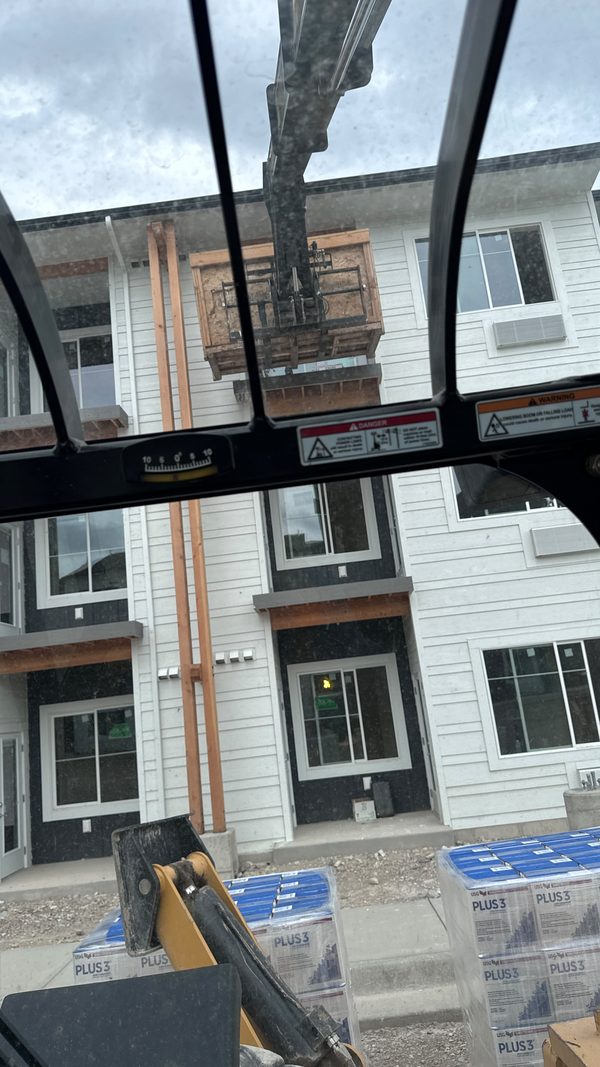 A lift raised against an apartment exterior under scaffolding